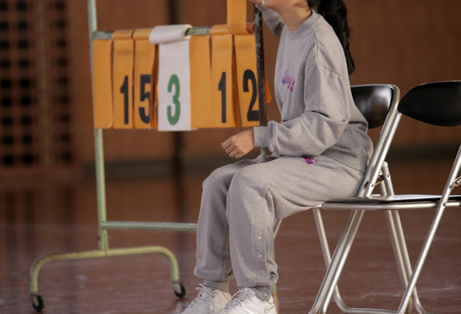 バスケのスウェットを着用して点数版の横に座っている女性