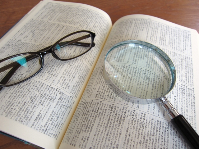 辞典の上においてある眼鏡と虫眼鏡